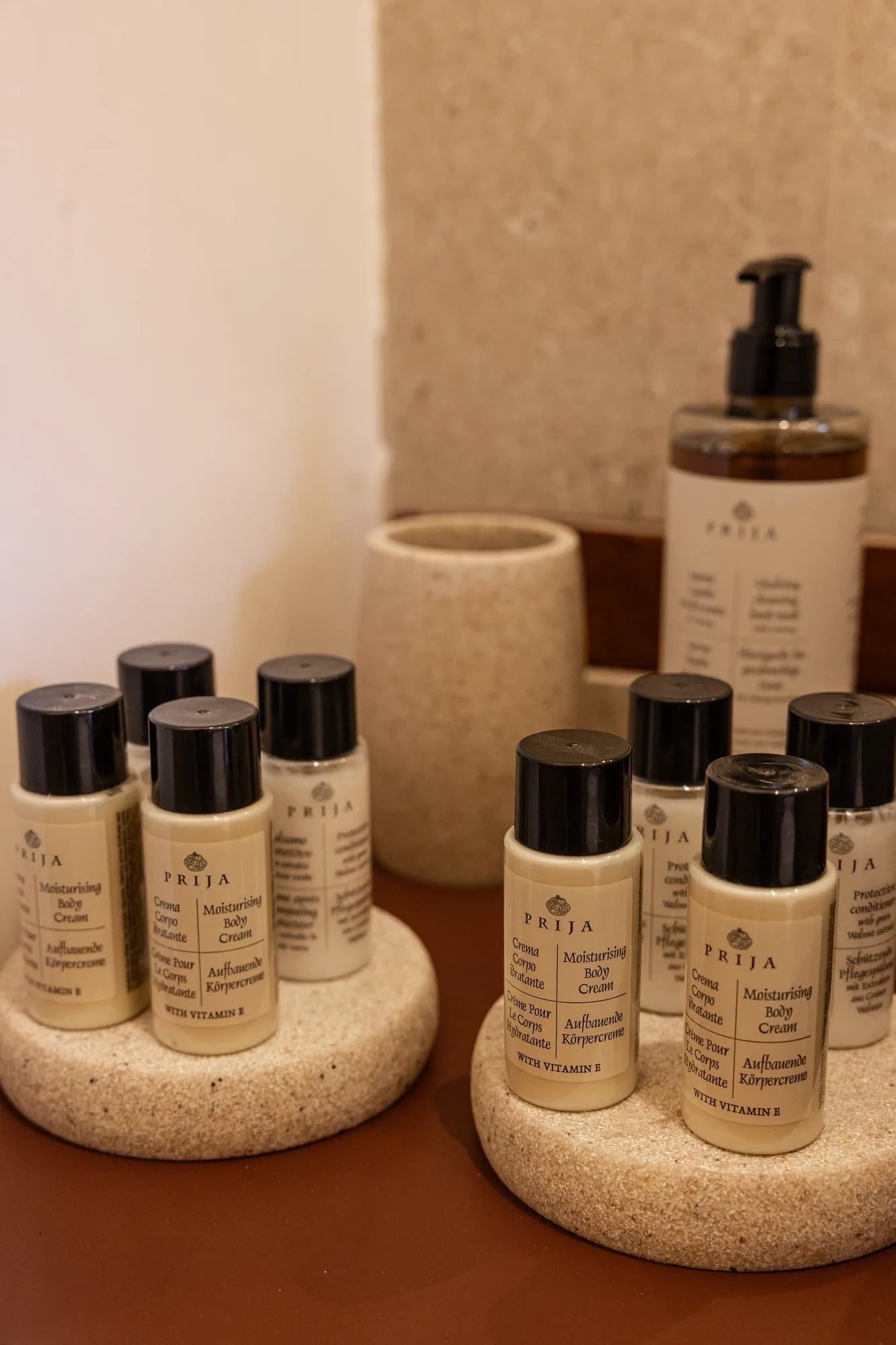 Bottles of body cream and cosmetic dispenser on stone supports