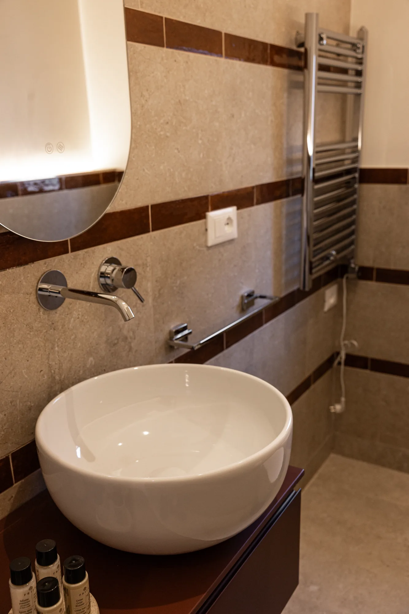 Bathroom sink with mirror, wall-mounted faucet, and chrome towel radiator