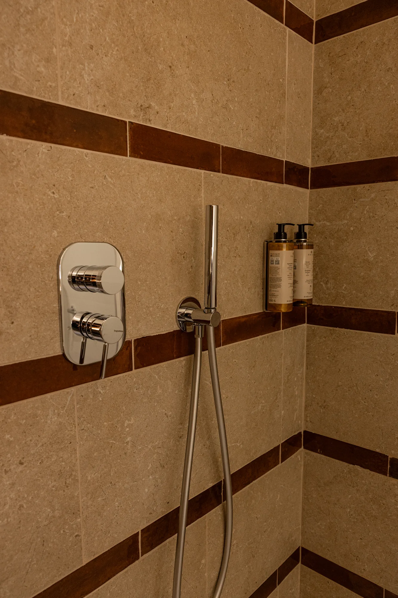 Shower with stone cladding, chrome mixer, and two soap dispensers