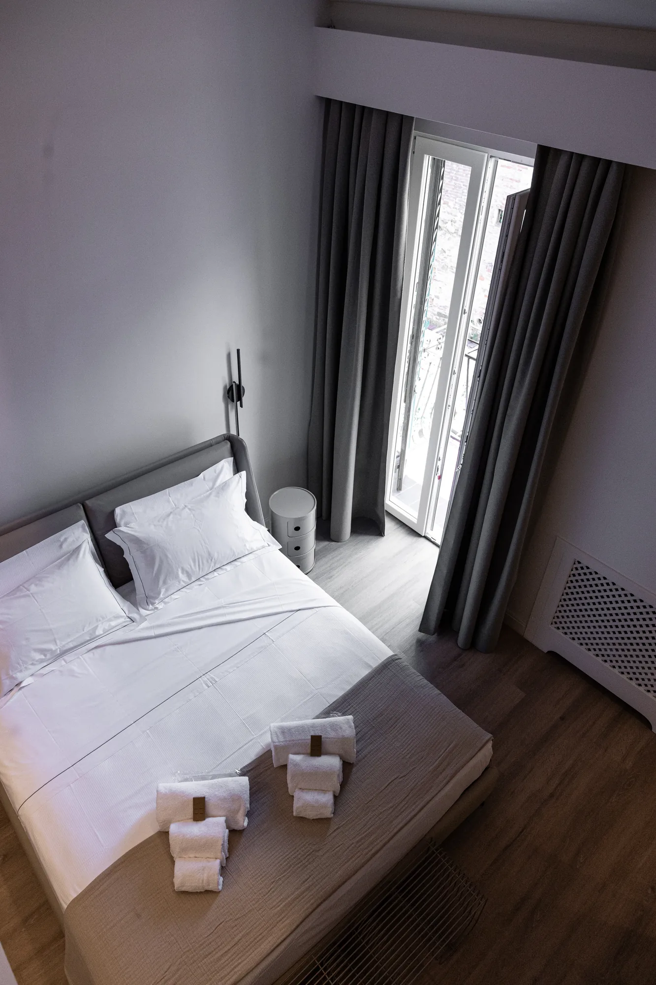 Modern bedroom with a double bed, dark curtains, and an open balcony