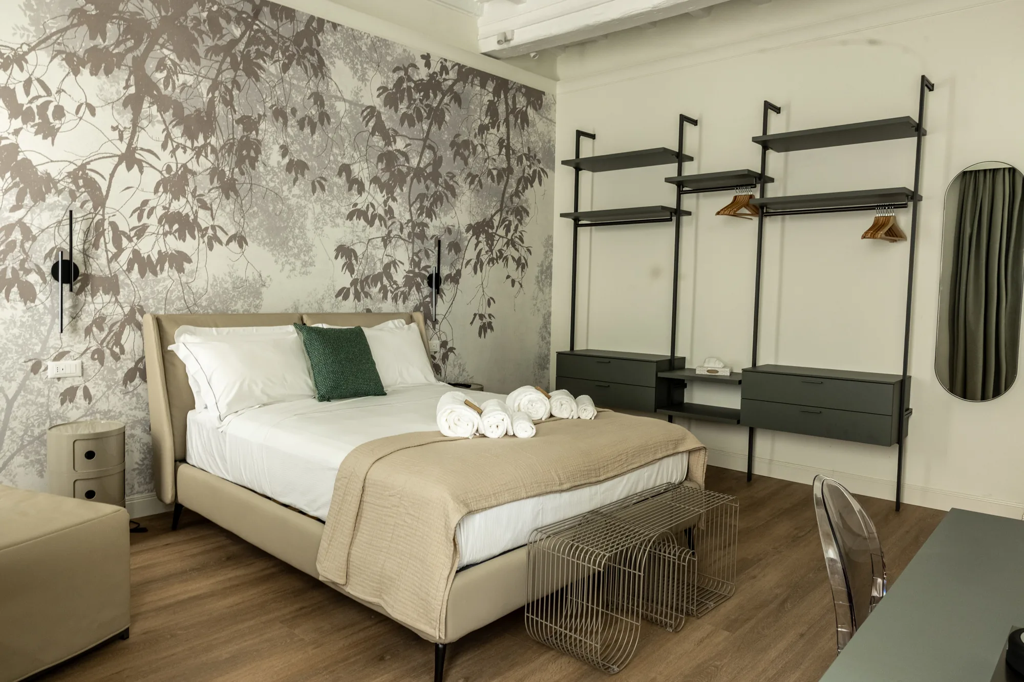 Camera da letto moderna con letto matrimoniale, carta da parati con foglie e scaffalature aperte