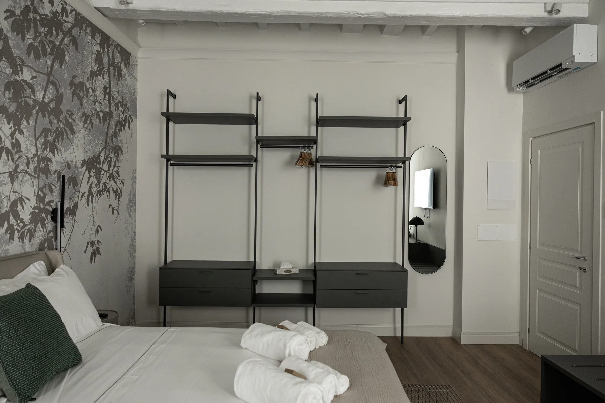 Camera da letto moderna con letto rifatto, armadi aperti, specchio e aria condizionata a parete