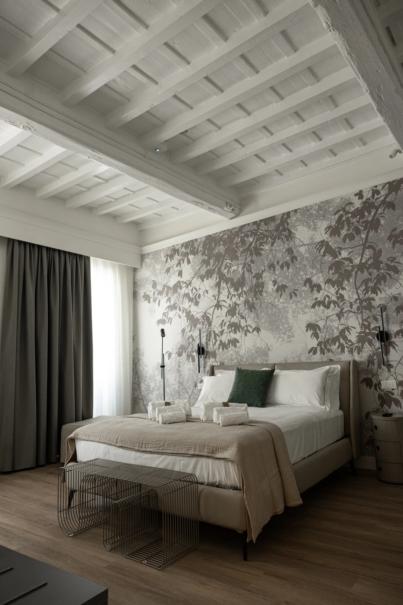 Camera da letto elegante con letto matrimoniale, carta da parati con motivi di foglie e tende scure