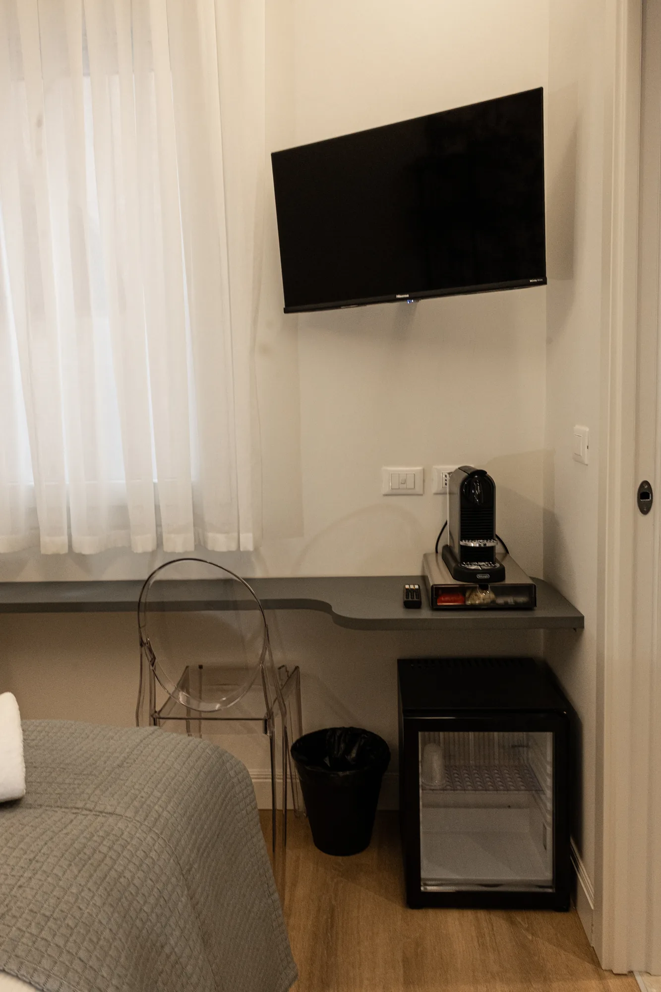 Camera d’albergo con TV a parete, macchina da caffè e mini frigo