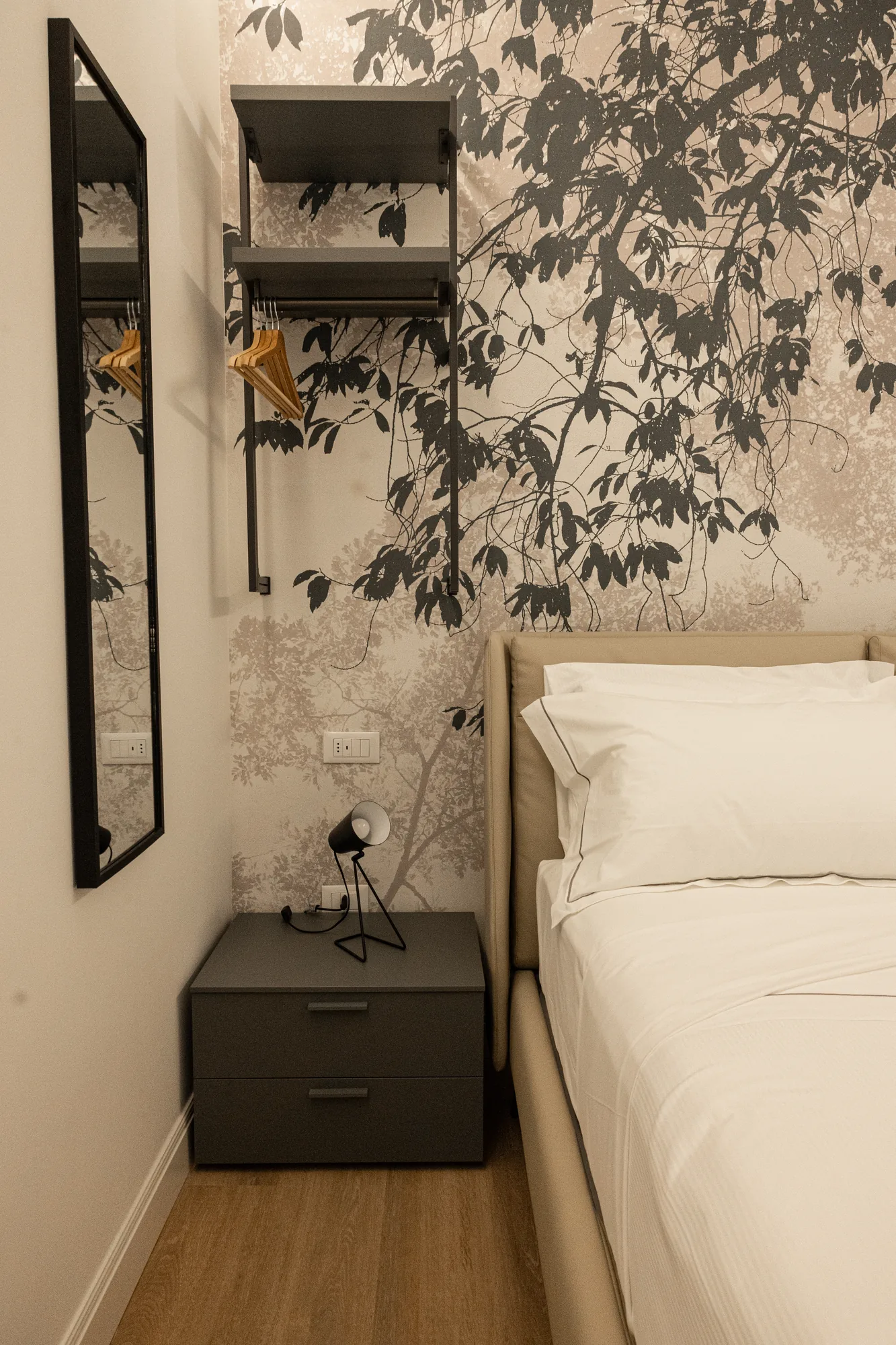 Camera da letto moderna con letto, comodino, specchio e armadio a parete con grucce