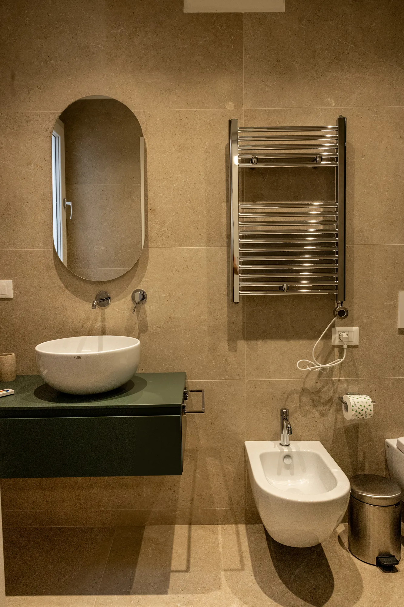 Bagno moderno con lavabo, specchio ovale, scaldasalviette e bidet