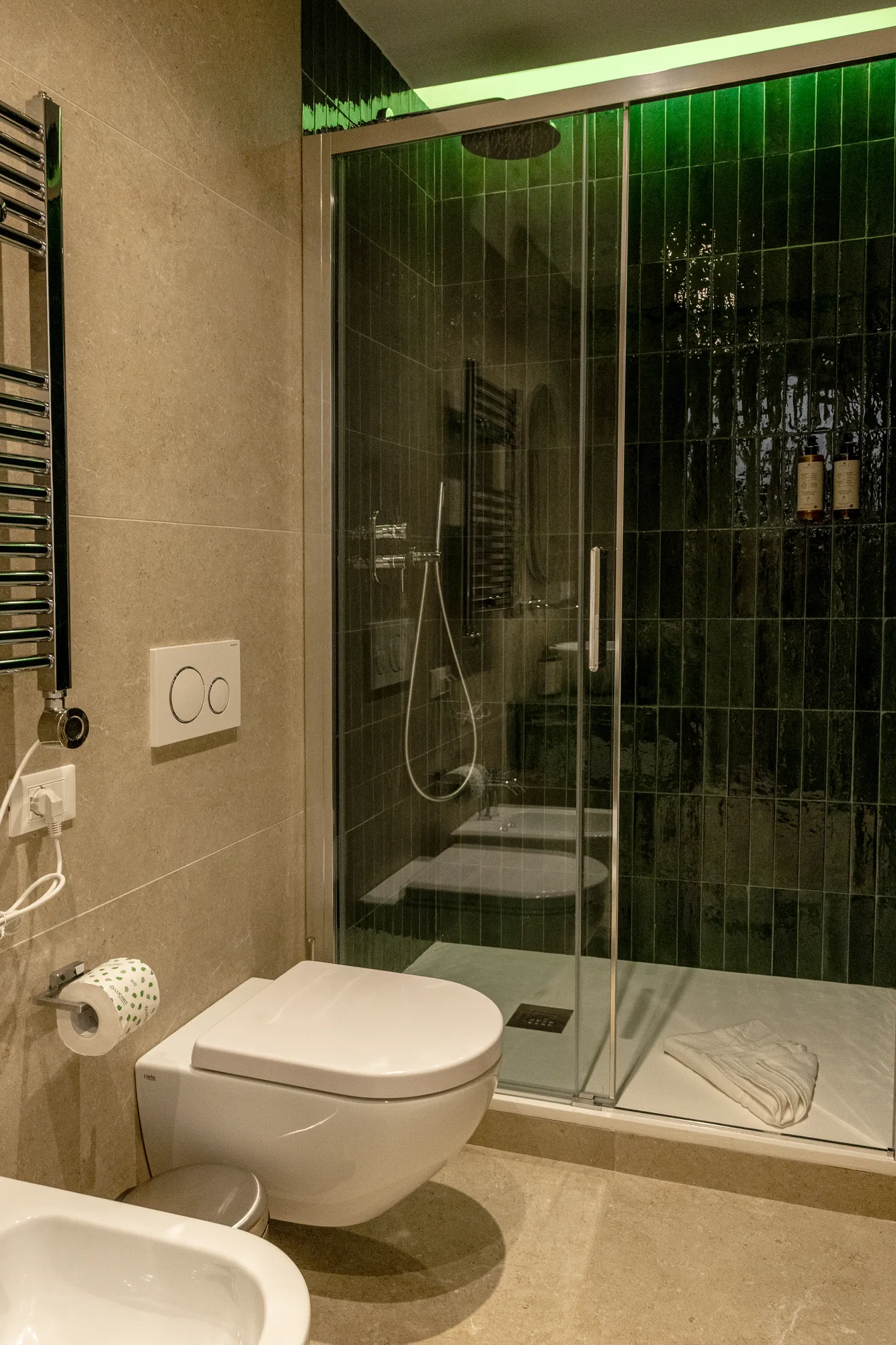 Bagno moderno con doccia in vetro, WC e bidet, rivestimenti beige e piastrelle verdi scure