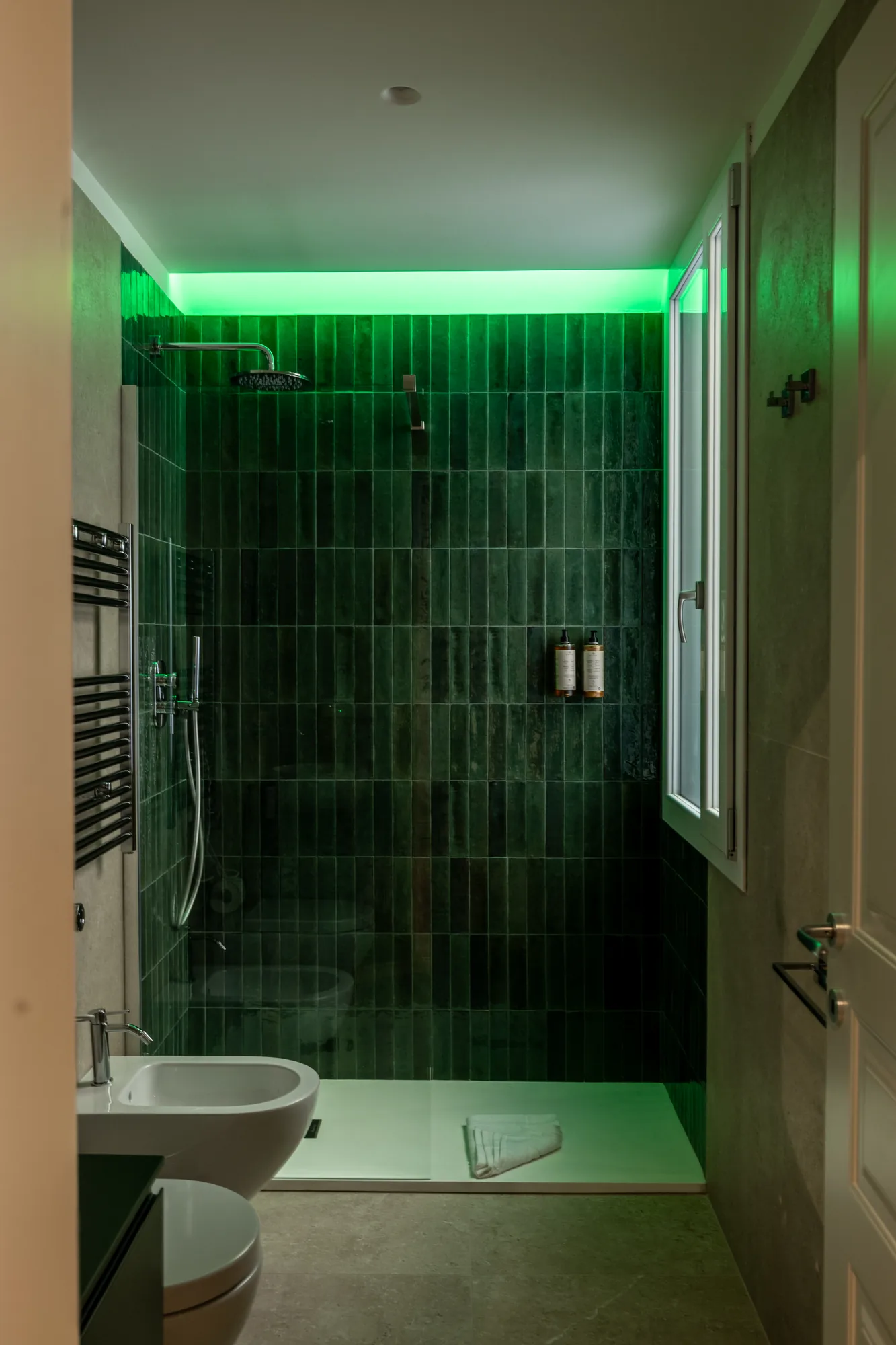 Modern bathroom with shower covered in green tiles and green LED light