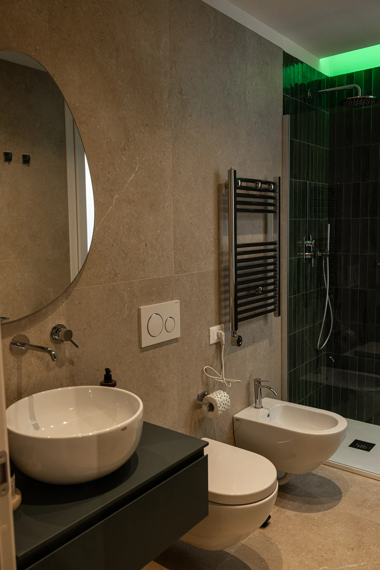 Modern bathroom with sink, bidet, shower, and round mirror