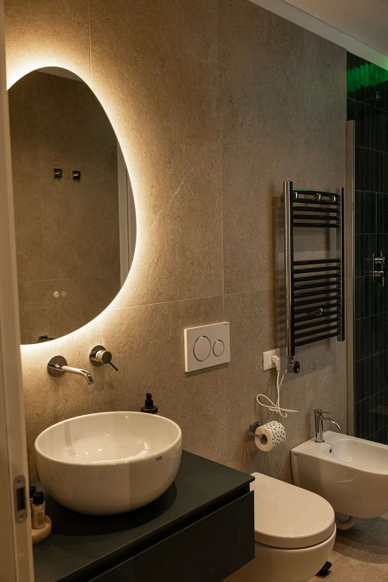 Modern bathroom with sink, backlit mirror, towel warmer, and bidet