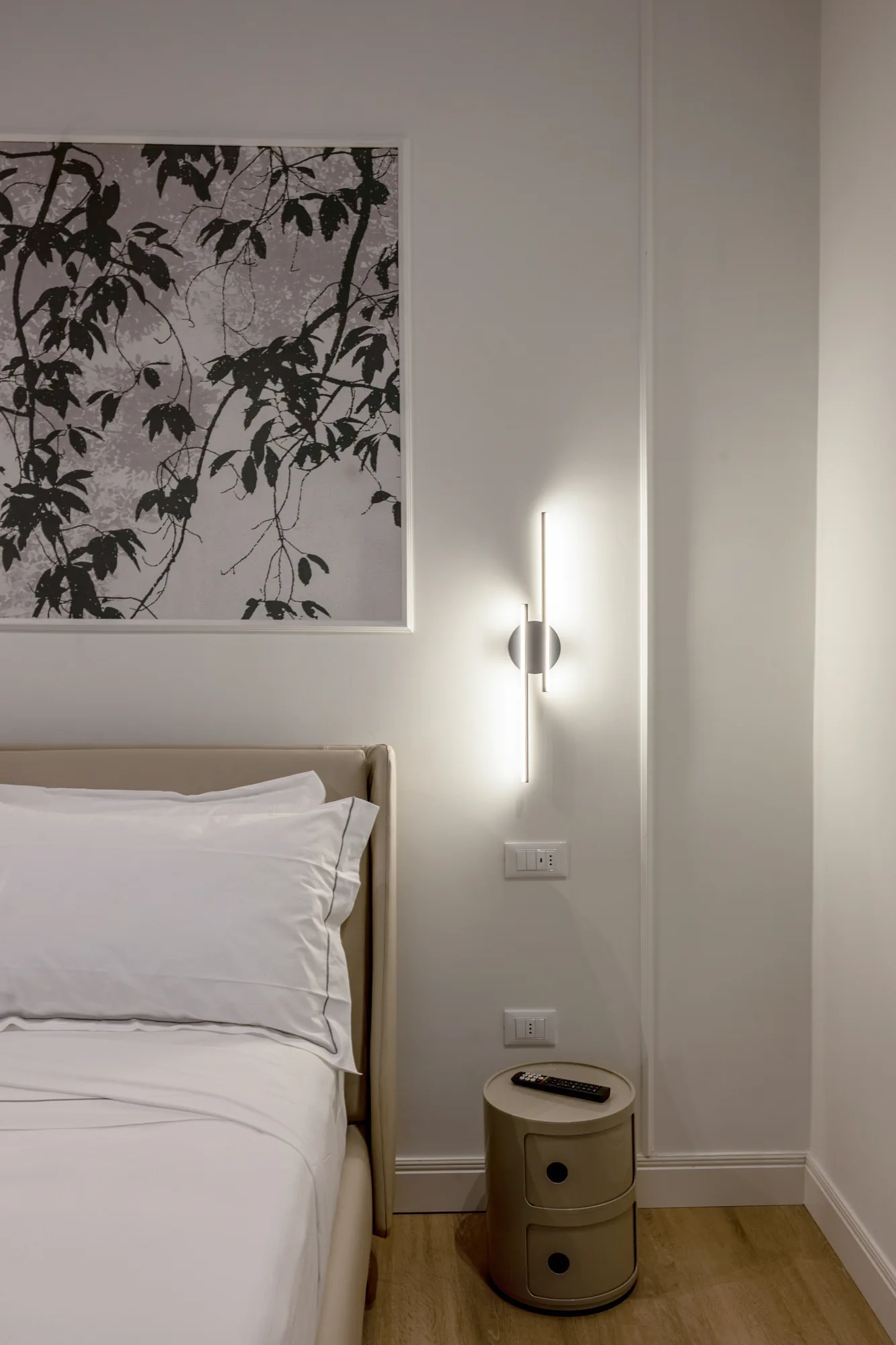 Modern bedroom with bed, wall lamp, and table with remote control