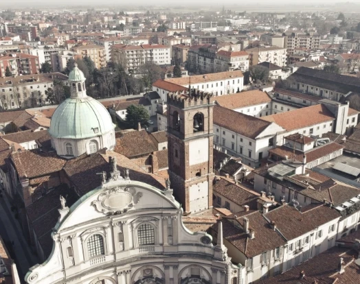 Veduta aerea di un centro storico con chiesa, cupola verde e campanile tra i tetti delle case